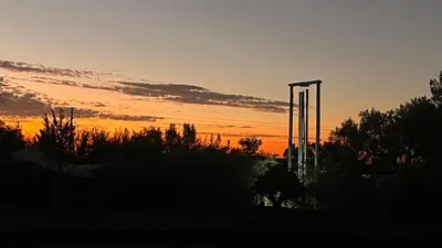 a sunset over a field with trees and bushes at Soul Oasis Urban Retreat in Centurion