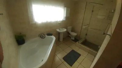 a bathroom with a tub and a shower and a toilet at Four Seasons Self-Catering Guest House in Graskop
