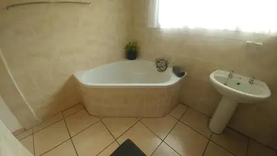 a bathroom with a bath tub and a sink at Four Seasons Self-Catering Guest House in Graskop