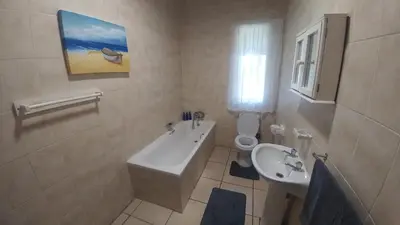 a white bathroom with a sink and a toilet at Four Seasons Self-Catering Guest House in Graskop