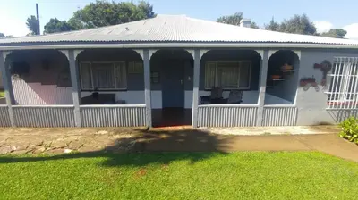 a white house with a porch and a yard at Four Seasons Self-Catering Guest House in Graskop