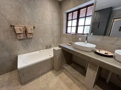 a bathroom with a sink and a tub and a sink and a mirror at MILIMA Big 5 Safari Lodge in Hoedspruit