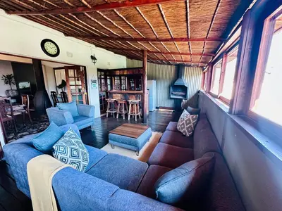 a living room with a couch and chairs and a clock at 49onMain Self Catering Holiday Home in Sabie