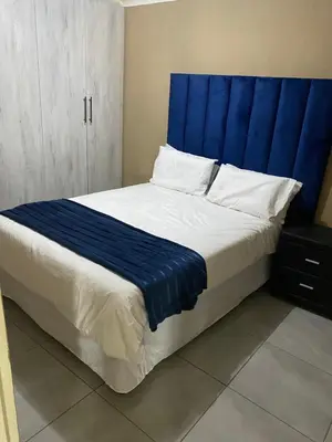 a bed with a blue headboard in a bedroom at RCB guesthouse in Burgersfort
