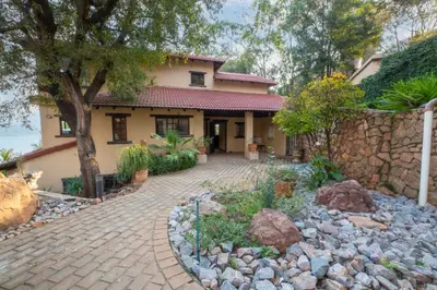 a house with a stone wall and a brick driveway at Vintage Serene Villa in Hartbeespoort
