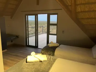 a bedroom with a bed and a large window at Tadima Lodge Mabalingwe in Mabula