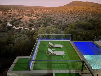 a glass house with two chairs and a swimming pool at Tadima Lodge Mabalingwe in Mabula
