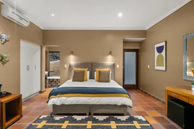 a bedroom with a large bed and a bathroom at Elements Private Golf Reserve House 296 in Bela-Bela