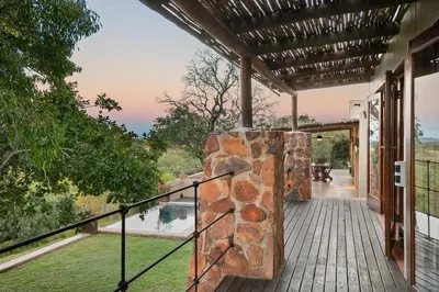 an outdoor deck with a stone wall at Elements Private Golf Reserve House 296 in Bela-Bela