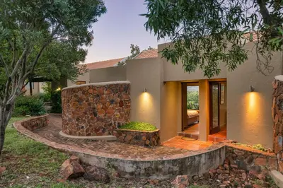 a house with a stone wall in the yard at Elements Private Golf Reserve House 296 in Bela-Bela