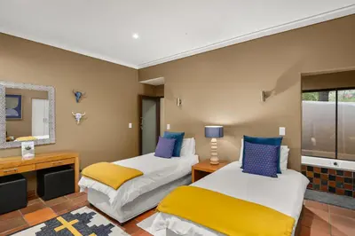 a bedroom with two beds and a mirror at Elements Private Golf Reserve House 296 in Bela-Bela