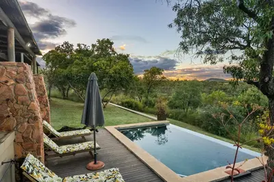 a pool with chairs and an umbrella next to a house at Elements Private Golf Reserve House 296 in Bela-Bela
