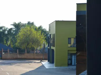 a green building in a parking lot next to a tree at The Pickle Residence in Tzaneen