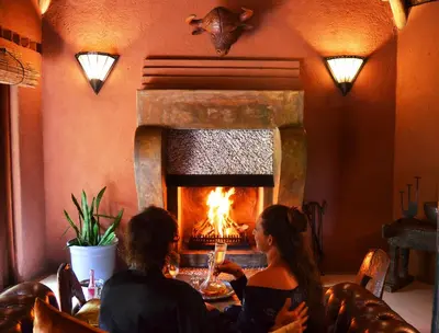 two women sitting at a table in front of a fireplace at Timamoon Lodge in Hazyview