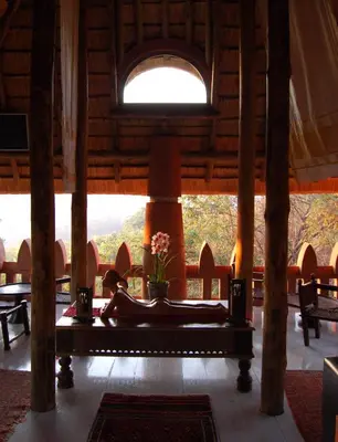 a woman laying on a bed in a room with a window at Timamoon Lodge in Hazyview