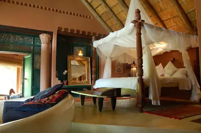 a bedroom with a canopy bed and a couch at Timamoon Lodge in Hazyview