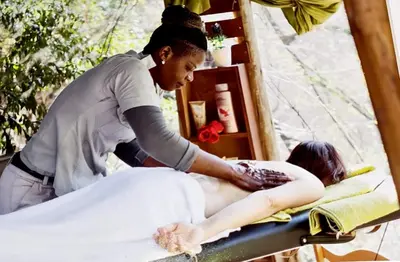 a woman getting a massage from a man on a bed at The Wild Olive Tree Camp in Manyeleti Game Reserve