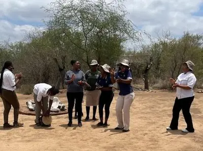 a group of people standing around in a field at The Wild Olive Tree Camp in Manyeleti Game Reserve
