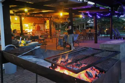 a man standing in front of a fire grill at Crocodile Bridge Safari Lodge in Komatipoort