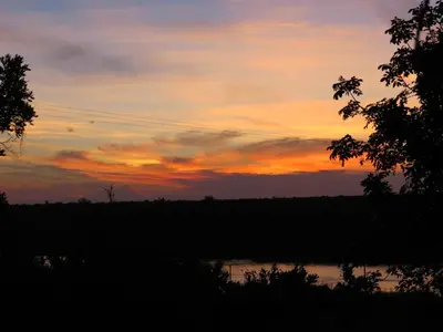 a sunset over a body of water with a tree at Crocodile Bridge Safari Lodge in Komatipoort