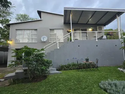 a house with a balcony and a table in the yard at The Calm Views Holiday Home in Hazyview