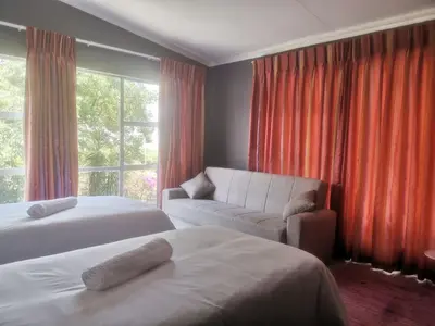 a bedroom with two beds and a couch and a window at The Calm Views Holiday Home in Hazyview