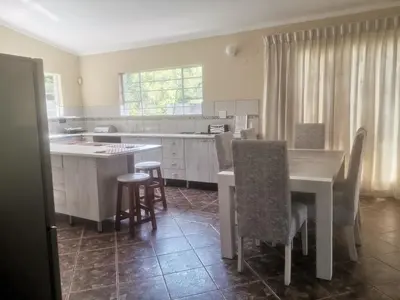 a kitchen with a table and some chairs in it at The Calm Views Holiday Home in Hazyview