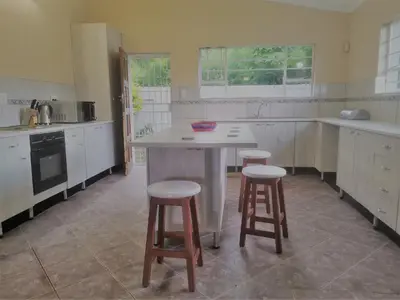 a kitchen with a table and stools in it at The Calm Views Holiday Home in Hazyview