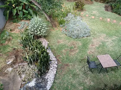 a table and chairs in a garden with plants at The Calm Views Holiday Home in Hazyview