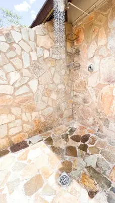 a shower with a stone wall with a waterfall at Baluleni Safari Lodge in Grietjie Nature Reserve
