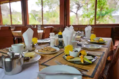 a wooden table with plates of food on it at Baluleni Safari Lodge in Grietjie Nature Reserve
