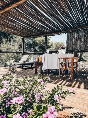 a table and chairs on a wooden deck with flowers at Baluleni Safari Lodge in Grietjie Nature Reserve