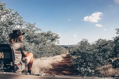 a woman sitting in the back of a truck on a dirt road at Baluleni Safari Lodge in Grietjie Nature Reserve