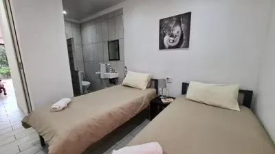 two beds in a room with a bathroom at Northwich Game Ranch in Louis Trichardt