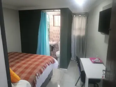 a bedroom with a bed and a bathroom with a sink at Munach Guest Lodge in Benoni