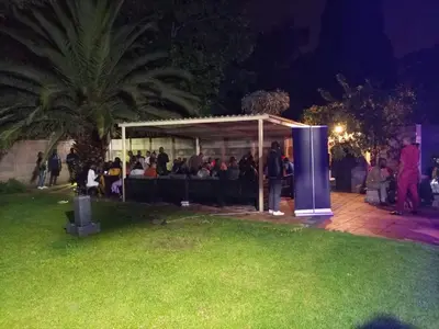 a group of people sitting under a gazebo at night at Munach Guest Lodge in Benoni