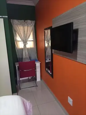 a bedroom with a red chair and a window at Munach Guest Lodge in Benoni