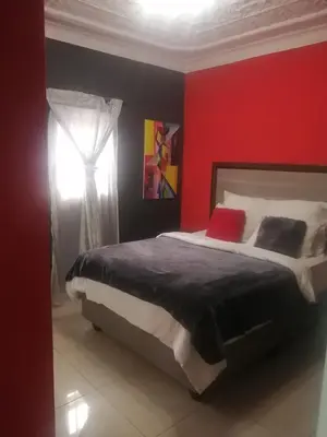 a bedroom with a large bed with a red wall at Munach Guest Lodge in Benoni