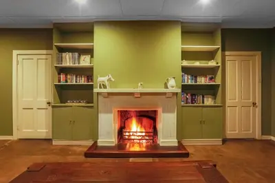 a fireplace in a living room with green walls at The Stone House in Die Winkler