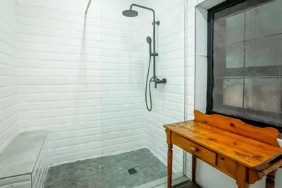 a bathroom with a shower and a wooden table at The Stone House in Die Winkler