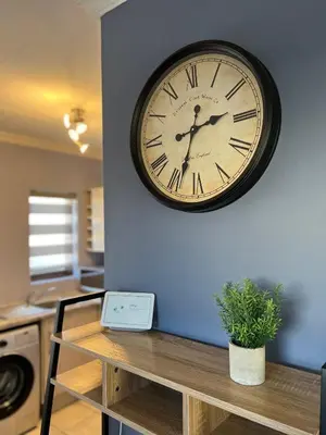 a clock on a wall above a table with a plant at Relaxing Getaway in Waterfall - close to Mall of Africa in Midrand