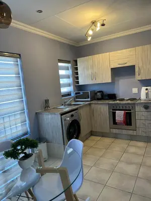 a kitchen with a table and chairs and a dishwasher at Relaxing Getaway in Waterfall - close to Mall of Africa in Midrand