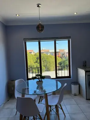 a dining room with a glass table and chairs and a window at Relaxing Getaway in Waterfall - close to Mall of Africa in Midrand