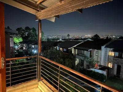 a balcony with a view of the city at night at Relaxing Getaway in Waterfall - close to Mall of Africa in Midrand