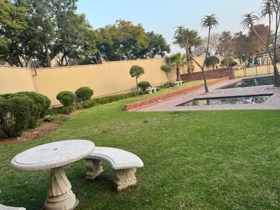 a stone bench sitting in the grass near a park at Relaxing Getaway in Waterfall - close to Mall of Africa in Midrand