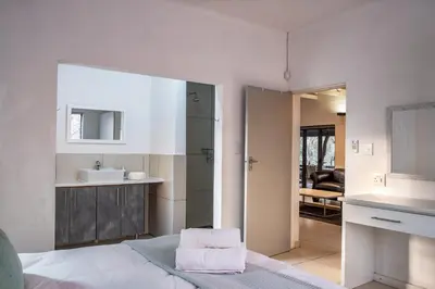 a bathroom with a bed and a sink and a mirror at Gemsbok Place in Marloth Park