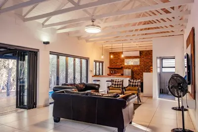 a living room with a couch and a kitchen at Gemsbok Place in Marloth Park