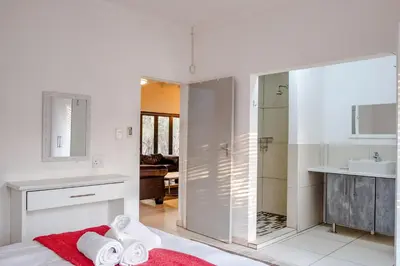 a white bathroom with a shower and a sink at Gemsbok Place in Marloth Park
