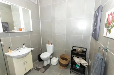 a bathroom with a sink and a toilet and a mirror at AfricaLove on Tiger in Pretoria