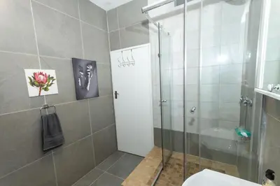 a bathroom with a shower stall and a toilet at AfricaLove on Tiger in Pretoria